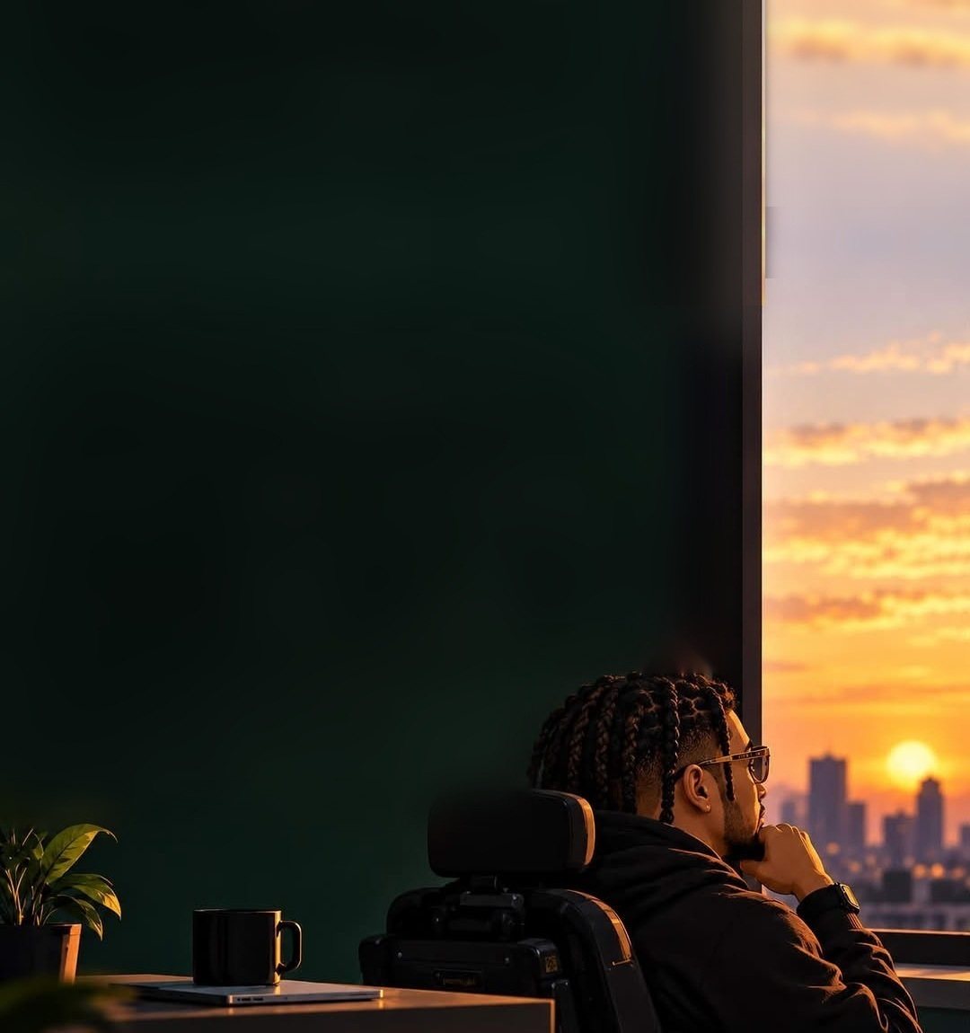 Illustration of Jon Thinxx at his desk, looking out a window at a city sunset
